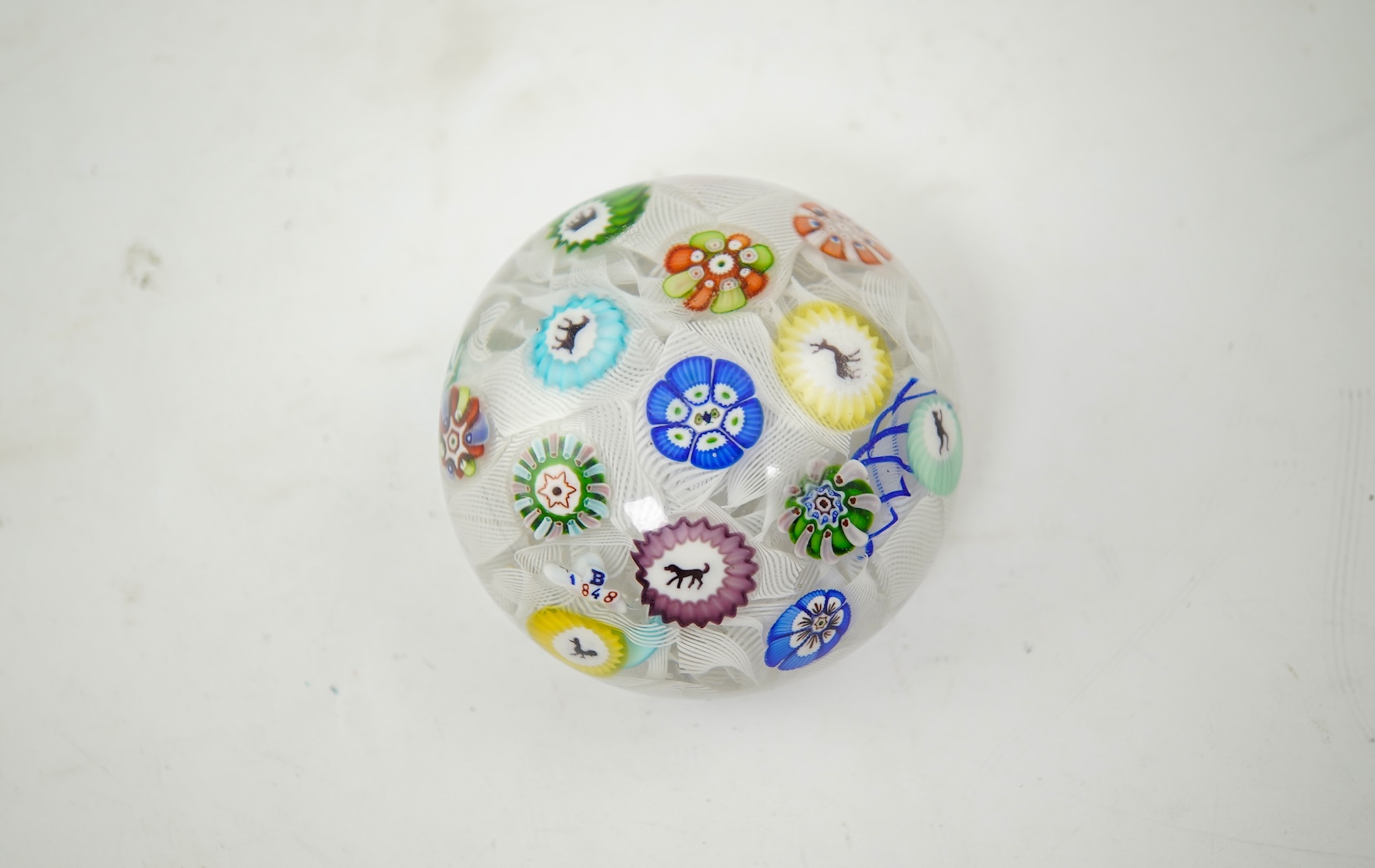 A Baccarat silhouette cane upset muslin ground paperweight, one cane dated 1848